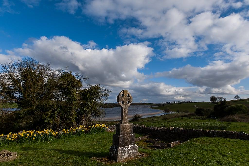 Obrázek Drumlane Abbey. water cemetery graveyard cross bluesky cavan daffodils celticcross drumlaneabbey
