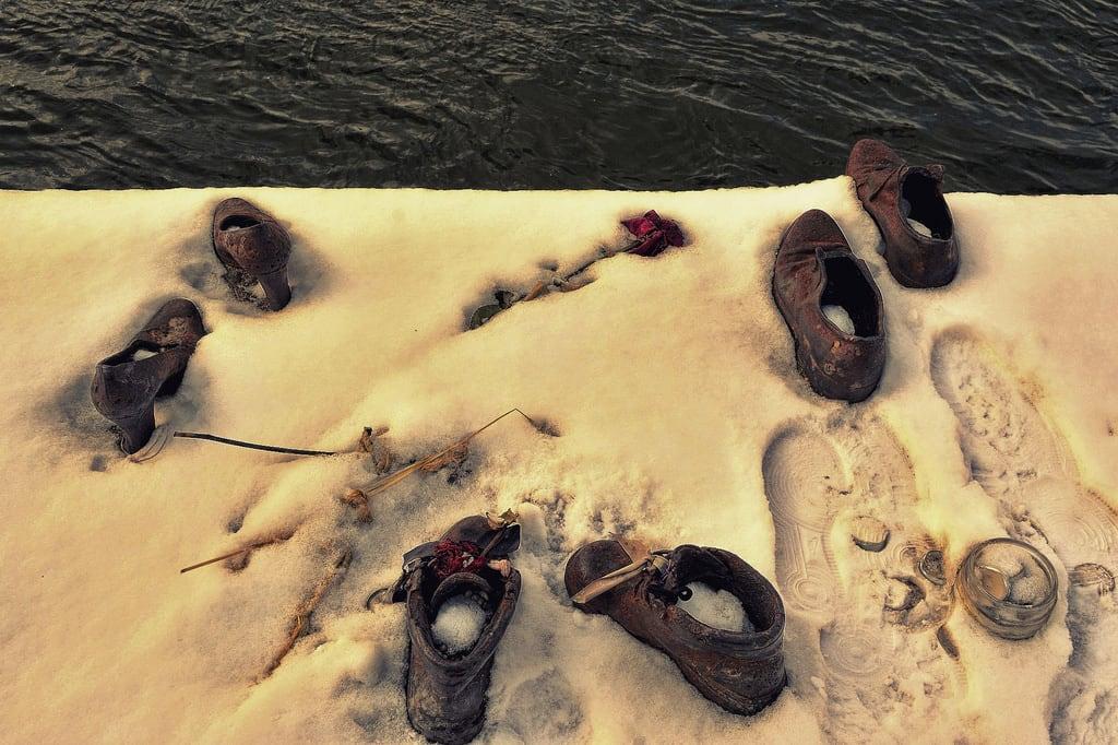 Afbeelding van Shoes on the Danube Bank. idantalljózsefrkp budapest hungary pest danuberiver cantogay gyulapauer memorial urban shoes iron sculpture nikon d5200 1855mm winter cold freeze freezing water flower candle snow snowing footprints holocaust glass jar
