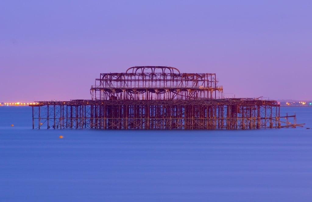 Immagine di West Pier. blue sea summer orange west water night coast pier iron brighton long exposure violet lilac nightime frame seafront remains silky
