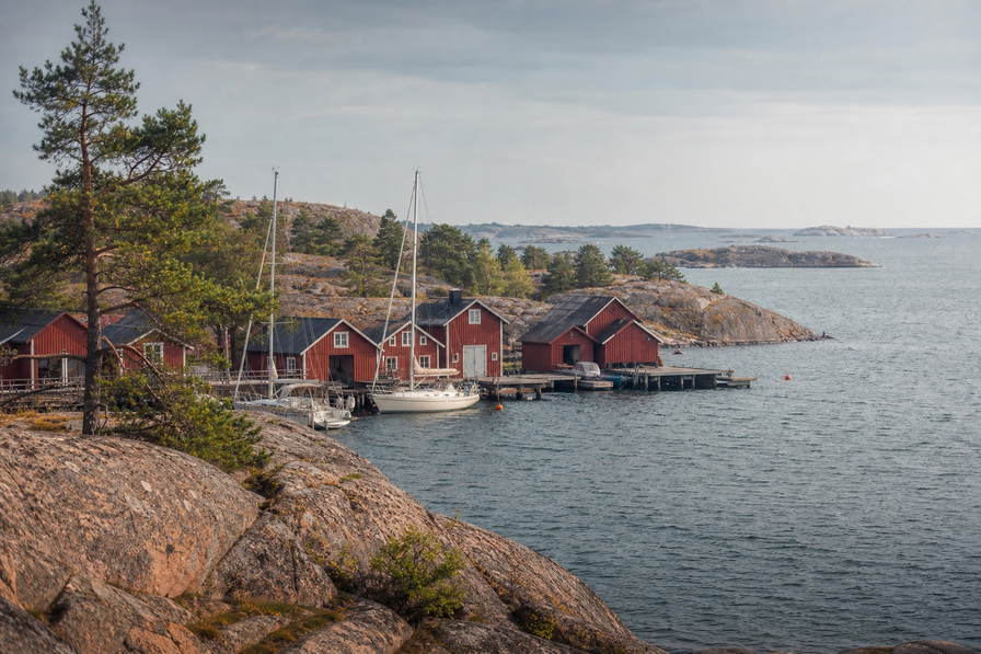 Aland-eilanden: graniet-esplanade van Mariehamn over Oostzee-chopbanden onder handels-cumulus, kopernevel van rode boothuizen naar perkamentstapels bij vestingruine Bomarsund en lint van Fasta Aland-scherrengordel bij Kobba Klintar plus weidegruis van eilandschapen in de hero - achtergrond voor EUR markt-streepjes, SEK veerboot-charter-stempelvouwen bij ponton-stapels van Westhaven van Mariehamn en rook-haring-weegbriefjesbanden.