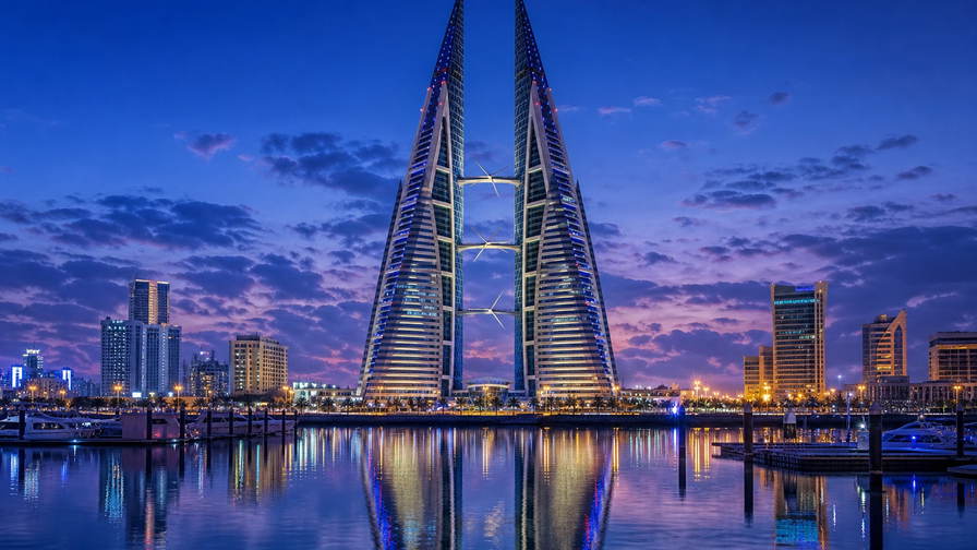 Bahrein: zeiltorens van het Bahrain World Trade Center in Manama vlechten marineturbinebladen in kobaltblauw schemerglas, specerijentocht onder de boog van Bab al-Bahrain richting dhow-kielzog bij parelwinkels in Muharraq en zeedijken van Qal'at al-Bahrain die stoom van tannur-brood vangen in de hero - achtergrond voor telbriefjes voor parelgewicht in Bahreinse dinar (BHD), weeglabels voor halwa-showq-zakken en gevouwen parkeerbonnen voor het circuit van Sakhir.