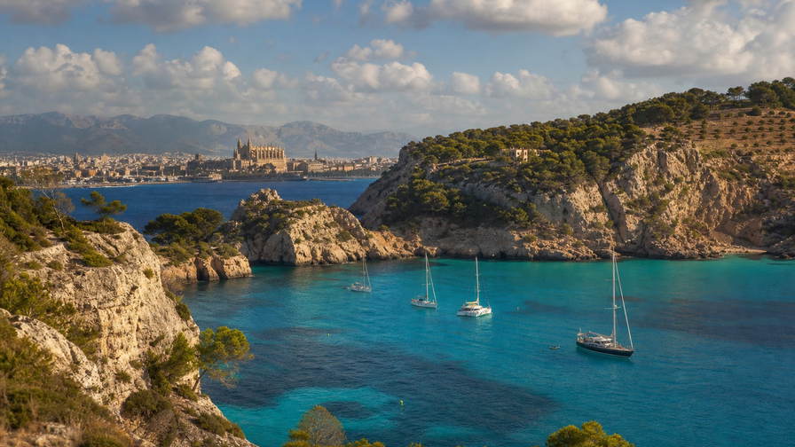 Balearen: zandstenen vlecht van kathedraal La Seu in Palma over Middellandse-Zee-chopbanden onder handels-cumulus, kopernevel van een baai op Menorca naar perkamentstapels bij zoutpannen Ses Salines op Ibiza en veerbootlint naar Formentera bij jachthaven-ponton-groeven plus amandelbloesem-stuifmeel in de hero - achtergrond voor EUR markt-streepjes, GBP jacht-charter-stempelvouwen bij glijkais van Port de Soller en sobrasada-worst-weegbriefjesbanden.