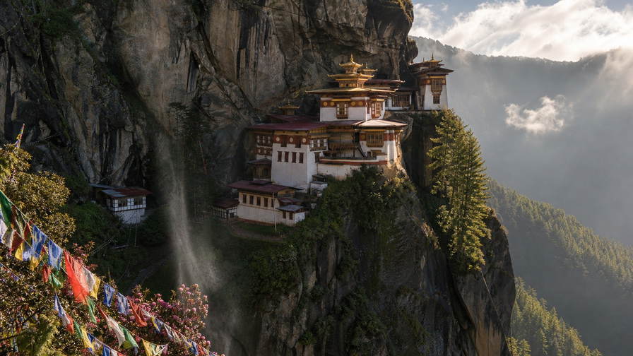 Bhutan: klif-vlecht van Taktsang Paro over moesson-cumulus-chopbanden, kopernevel van witgekalkte dzongs naar perkamentstapels bij Thimphu en gebedsvlaggenlint van Punakha bij boerderij-kade-groeven plus jeneverbes-wierookstof in de hero - achtergrond voor BTN markt-streepjes, INR grenshandel-charter-stempelvouwen bij glijkais van Phuentsholing en rode-rijst-weegbriefjesbanden.