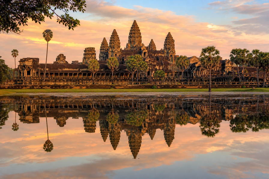 Cambodja: lotustorens van Angkor Wat die zijderoze vijverspiegelingen vlechten bij ochtendlicht in de jungle, palen van stelzenhuizen op het Tonlé Sap richting weefschiet-geratel in de gangen van de Russian Market in Phnom Penh en zilvermist boven rijstvelden in Battambang in de hero - achtergrond voor streepjes bij noedelkarren in Cambodjaanse riel (KHR), waszegels op potten met prahok-pasta en gevouwen bonnen aan keycords voor tempelpassen.