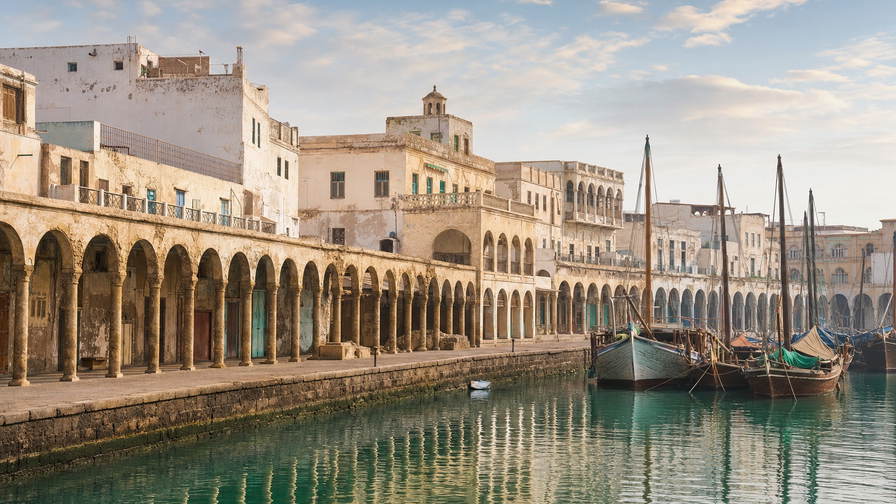 Eritrea: koraalkalken Ottomaanse arcades in Massawa die dhow-masten in het ochtendhavenglas verdubbelen, rationalistisch stucwerk in Asmara in stofamber van de helling en ondiepe Dahlak-wateren boven bleke kalkbodems in de hero - achtergrond voor wisselbriefjes in Eritrese nakfa (ERN), grillrookbonnetjes voor rode snapper in Massawa en telstapels aan de keih-bahli-gebaktoonbank aan Harnet Avenue.