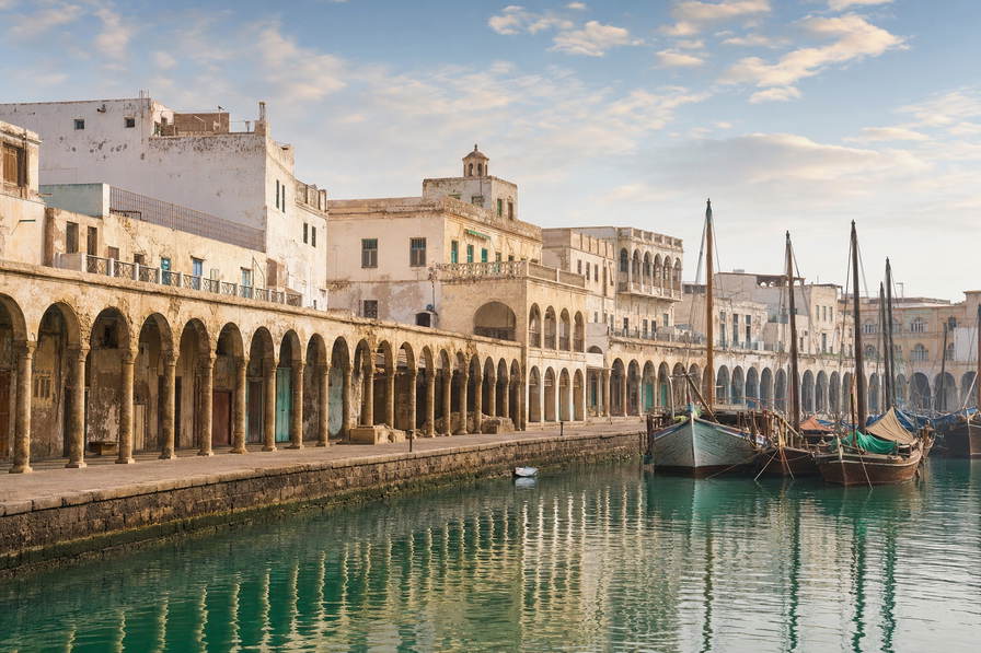 Eritrea: koraalkalken Ottomaanse arcades in Massawa die dhow-masten in het ochtendhavenglas verdubbelen, rationalistisch stucwerk in Asmara in stofamber van de helling en ondiepe Dahlak-wateren boven bleke kalkbodems in de hero - achtergrond voor wisselbriefjes in Eritrese nakfa (ERN), grillrookbonnetjes voor rode snapper in Massawa en telstapels aan de keih-bahli-gebaktoonbank aan Harnet Avenue.