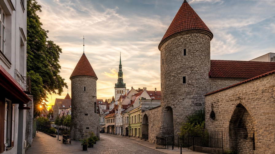 Estland: middeleeuwse Hanzepakhuizen in de Tallinse haven, mist op vlonderpaden door hoogveen en dennenduinen aan de Oostzee in de banner - scène voor roggebrood, sauna-toeslagen en ferryhut-upgrades.