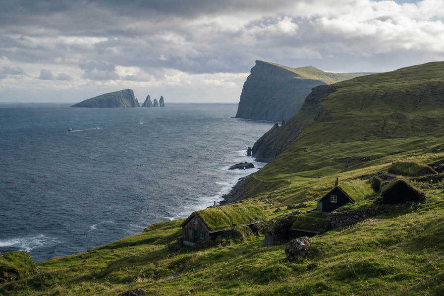Faeroeer-eilanden: basalt-klif-vlecht van Vestmanna over Atlantische chopbanden onder handels-cumulus, kopernevel van een turf-dak-dorp naar perkamentstapels bij haven Torshavn en lint van meer Sorvagsvatn naar stapels bij Mykines plus weidegruis van Faeroeer-schapen in de hero - achtergrond voor DKK markt-streepjes, EUR helikopter-charter-stempelvouwen bij glijkais van vliegveld Vagar en kabeljauw-rook-weegbriefjesbanden in Klaksvik.