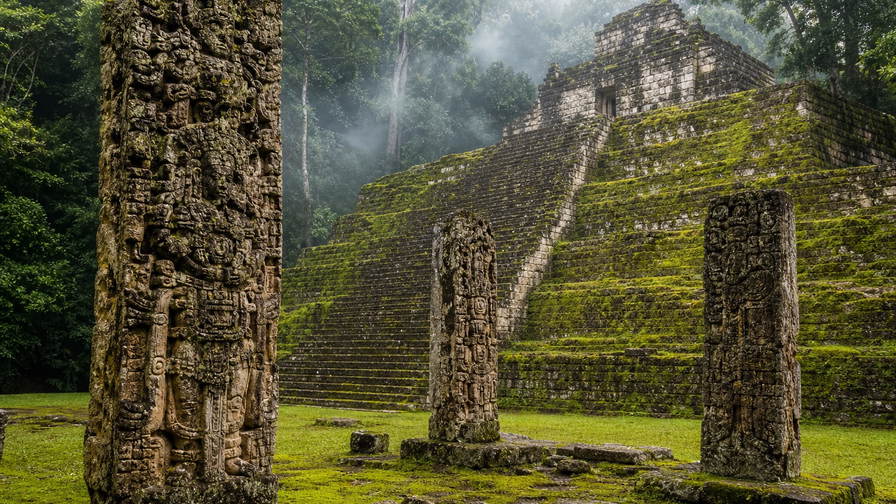 Honduras: mos op Maya-stelen in Copán met kalkstenen banden van de Hierogliefentrap onder stomende jungle-cumulus, turkooizen rifvingers bij Roatán naar krijtwitte zandtongen op Cayos Cochinos en koperkleurig trommelglanz langs de kade van La Ceiba met stof van microlot-perksels uit Santa Barbara in de hero - achtergrond voor baleada-marktbrieven in lempira (HNL), gevouwen stempels van veerbootbagage op het dek en weegbriefjes voor lionvisfilet op ijs uit Roatán.