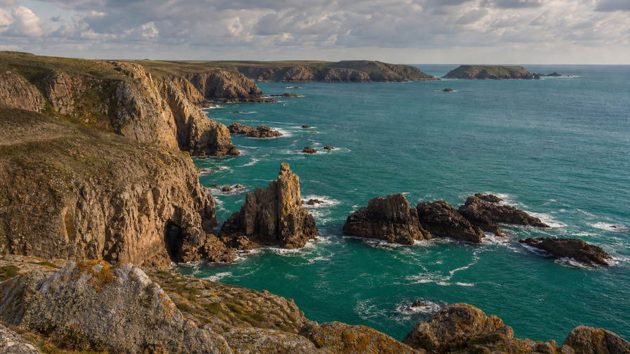 Jersey: graniet-vlecht van Corbière over St Ouen-baai golfbanden onder handelsstapelwolken, kopernevel van noordkust naar perkamentstapels bij jachthaven St Helier en lint van Bouley Bay bij groeven in haven Gorey plus akkerstof van Jersey Royal-aardappelruggen in de hero - achtergrond voor GBP markt-streepjes, EUR veerboot-charter-stempelvouwen bij marina-glijkais en oester-weegbriefjesbanden in St Aubin.