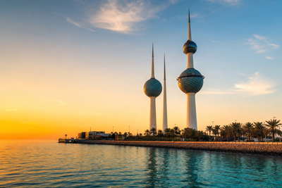 Koeweit: roestvrijstalen koepels van de Koeweit Towers in koperkleurige schemer boven de Arabische Golf, mashrabiya-dakschaduwen van Souq Al-Mubarakiya richting dhow-lak van de haven Shuwaikh en stoom van dadelspersen onder blikken luifels in de hero - achtergrond voor kassabonnen van geldwisselaars in de goudsoek in Koeweitse dinar (KWD), weeglabels voor cardamomzakken voor machboos en gevouwen girocheques voor wachtrijen bij overschrijvingen.