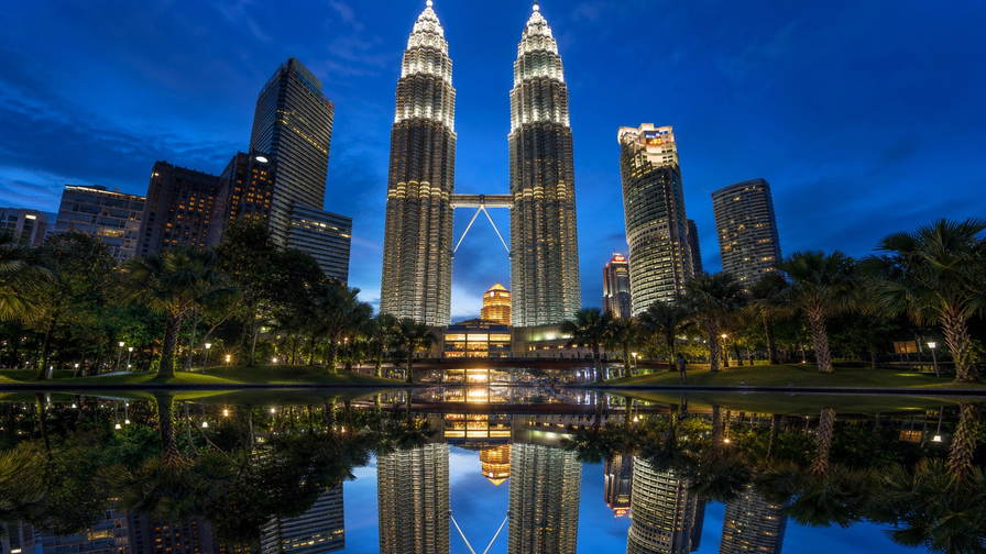 Maleisië: roestvrijstalen ruggengraat van de Petronas-tweeling die kobaltblauw spiegelglas van het KLCC-bassin vlecht in het blauwe uur, pastelkleurige winkelhuizen in George Town op Penang richting nasi lemak-stoom op bananenblad op Jonker Walk bij nacht in Malakka en wolkencolliers rond de top van Kinabalu op Borneo in de hero - achtergrond voor streepjes bij spiesjes op nachtmarkten in Maleisische ringgit (MYR), grammenstickers voor Musang King-durian en gevouwen tickets voor boomkroonpaden.