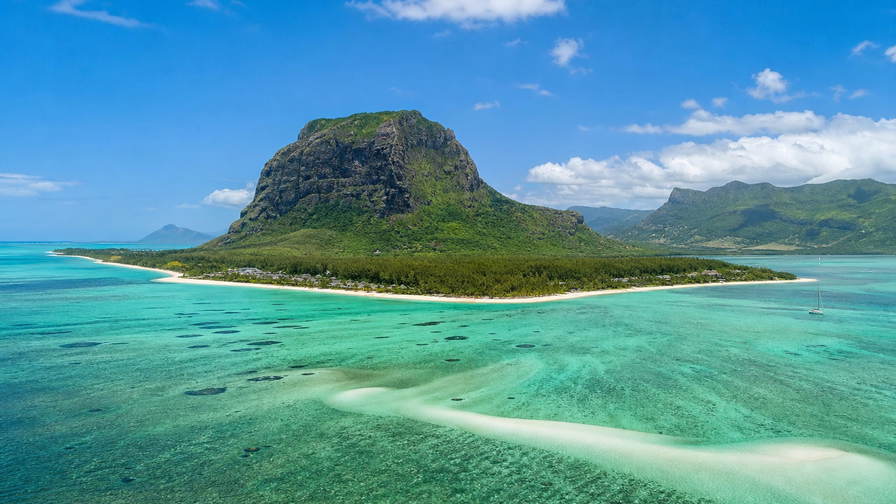 Mauritius: lagunespiegel bij Le Morne onder de basaltpiek Le Morne Brabant, stoom van dholl puri op de centrale markt van Port Louis bij zonsopgang en haarspeldbochten door theeplantages richting Grand Bassin in de hero - achtergrond voor rougaille-inktvis van de grill, kassabonnen in Mauritiaanse roepies (MUR) en weekprijzen voor kustvilla's met tweetalige contracten.