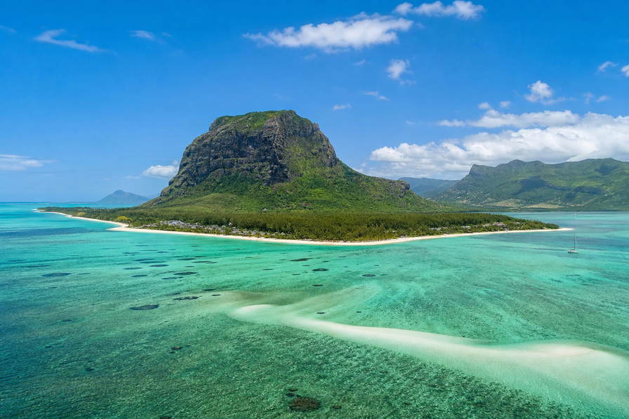 Mauritius: lagunespiegel bij Le Morne onder de basaltpiek Le Morne Brabant, stoom van dholl puri op de centrale markt van Port Louis bij zonsopgang en haarspeldbochten door theeplantages richting Grand Bassin in de hero - achtergrond voor rougaille-inktvis van de grill, kassabonnen in Mauritiaanse roepies (MUR) en weekprijzen voor kustvilla's met tweetalige contracten.