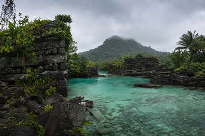 Micronesia: jadeglazen lagunevlaktes bij Chuuk die silhouetten van oorlogswrakken in koraalbloemen onder grijze stratus vlechten, nevelige basaltring van Nan Madol op Pohnpei naar betelnootpiramides in de schaduw van de Colonia-markt en glans van kalkstenen rai-schijven in ondiepe Yap-lagune in de hero - achtergrond voor briefjes voor wrakduiken in US-dollars (USD), gevouwen dekstickers op schepen tussen de staten en weegbriefjes voor gewicht aan sakau-kavawortel in pond.