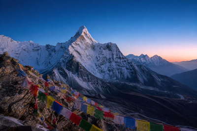 Nepal: ijsfluiten van Ama Dablam die gebedsvlaggenkam boven veekralen van Namche Bazaar kaderen, oogstrepen van de Boudhanath-stupa in Kathmandu richting petroleumlampgloren in Everest-theehuizen en turkooizen roeiriemeling op Fewa-meer in Pokhara in de hero - achtergrond voor gevouwen TIMS-trekkingvergunningen in Nepalese roepies (NPR), brandstofbonnetjes voor yakmest en stapels vinkjes op stoommanden voor momo.