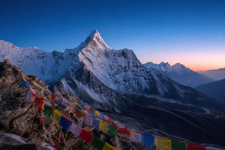 Nepal: ijsfluiten van Ama Dablam die gebedsvlaggenkam boven veekralen van Namche Bazaar kaderen, oogstrepen van de Boudhanath-stupa in Kathmandu richting petroleumlampgloren in Everest-theehuizen en turkooizen roeiriemeling op Fewa-meer in Pokhara in de hero - achtergrond voor gevouwen TIMS-trekkingvergunningen in Nepalese roepies (NPR), brandstofbonnetjes voor yakmest en stapels vinkjes op stoommanden voor momo.