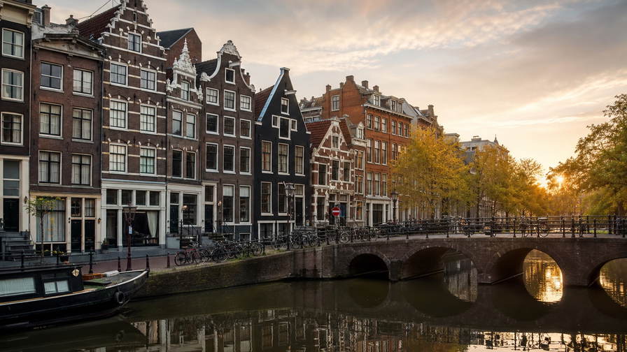 Nederland: bakstenen topgevels, grachtenbruggen en vlakke polderhorizon in de hero - past bij fietsstad-boodschappen, bruine kroegen en studentenhuur-tabellen.