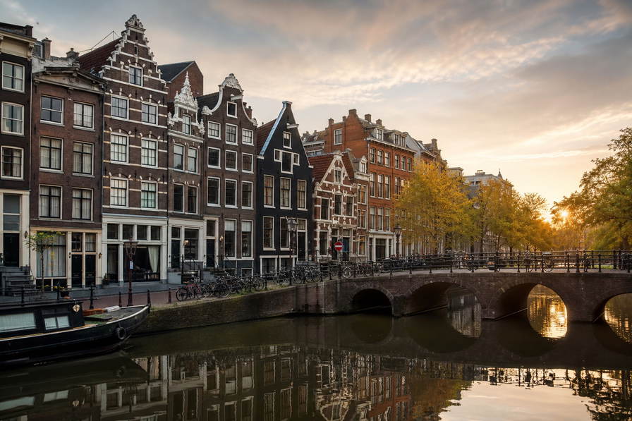 Nederland: bakstenen topgevels, grachtenbruggen en vlakke polderhorizon in de hero - past bij fietsstad-boodschappen, bruine kroegen en studentenhuur-tabellen.