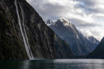 Nieuw-Zeeland: sneeuwrug van de Southern Alps die Milford Sound-mist vlecht langs zwarte wanden van water, gloed van tussock-ruggen bij Queenstown, zwavelstoom over Rotorua naar staalkabels van de kabeltram in Wellington en pinot-noir-wijnrijen in Central Otago in de hero - achtergrond voor hutboekingsbriefjes in Nieuw-Zeelandse dollars (NZD), dekstempels van de Interislander-veerboot door de Cookstraat en weegbriefjes voor honingpotjes op de boerenmarkt.