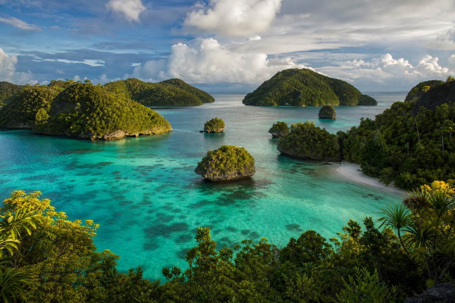 Palau: paddenstoelvormige kalksteeneilanden van de Rock Islands die melkachtig-turkooizen binnenlagunecorridors vlechten onder kobaltcumulus, zilveren manta-V-wakes in de German Channel naar rieten dakfirstsilhouetten van bai-vergaderhuizen in Koror en cyaan rifwanddraden bij Blue Corner in de hero - achtergrond voor briefjes voor Rock-Islands-tours in US-dollars (USD), gevouwen stempels op duikroutes naar Blue Hole en weegbriefjes voor kusthandwerkweefsels.
