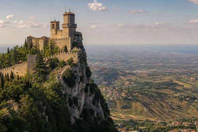 San Marino: kalkstenen klifkruinen vlechten kanteelmuur-schaduwen, terracotta-dakstapels klimmen Titano-achtige ruggen en Adriatische zilvernevelbanden in de hero-foto - visuele intro voor EURO-kassabonnen in duty-vriendelijke winkels, pasta-truffel-horeca in het heuvelstadje en huur-ladders voor terrasgasten in Borgo.
