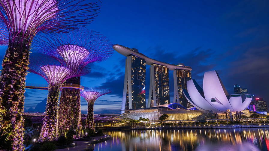 Singapore: verticale supertree-tuinen in Marina Bay die paarse lasernevel van lotusblaadjes van ArtScience Museum vlechten, neonrimpelingen bij Clarke Quay richting satérook van hawkercentra onder wasgoed-geometrie aan HDB-flats en robijnrode avondstrepen van de kabelbaan naar Sentosa in de hero - achtergrond voor jetons bij hawkerkramen in Singaporese dollar (SGD), gevouwen bonnen voor kopi-o met sokfilter en stapels EZ-link-opwaardeerstrookjes.