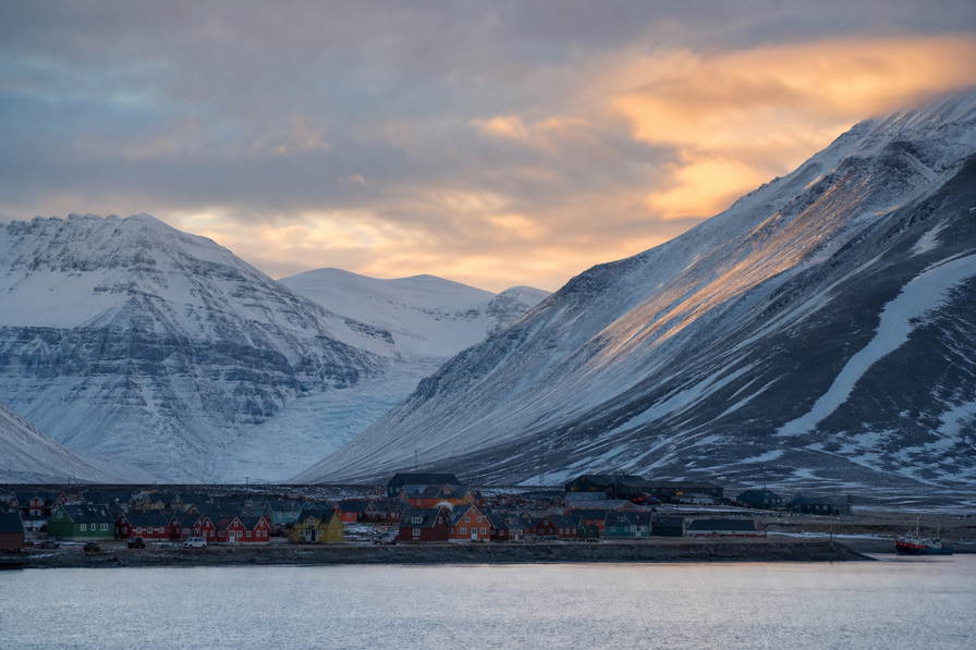 Svalbard en Jan Mayen: houten esplanade van Longyearbyen over chopbanden van Adventfjorden onder handels-cumulus, kopernevel van gletsjer naar perkamentstapels bij landingsbaan Ny-Alesund en lint van smeltwater van Isfjord bij gelaagde ijsgroeven plus weidegruis van rendierweiden in de hero - achtergrond voor NOK markt-streepjes, EUR expeditie-cruise-charter-stempelvouwen bij ponton-stapels van steenkoolkaai en rook-kabeljauw-weegbriefjesbanden.