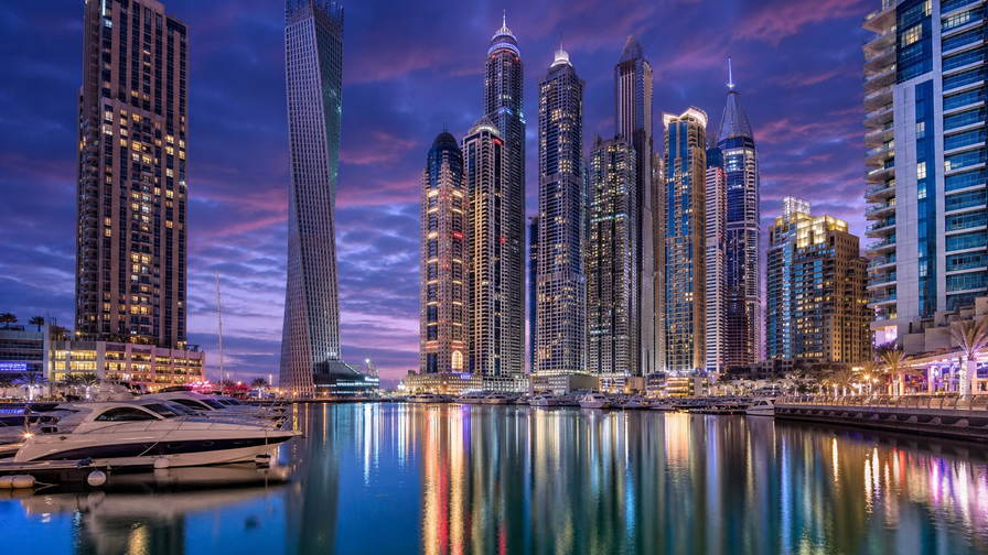 Verenigde Arabische Emiraten: glazen gevels van Dubai Marina die jachtkielzicht dubbelen in het blauwe uur, parelmoer-rimpelingen van koepels in Abu Dhabi richting LED-gloed van de goudsouk in Deira en nevelbanden van duin naar beton op Saadiyat in de hero - achtergrond voor Salik-tolchipafdrukken in VAE-dirham (AED), grammenbriefjes voor 22-karaats gouden kettingen en stapels aankruisvakjes op vrijwaringsformulieren voor woestijnsafari-duinritten.